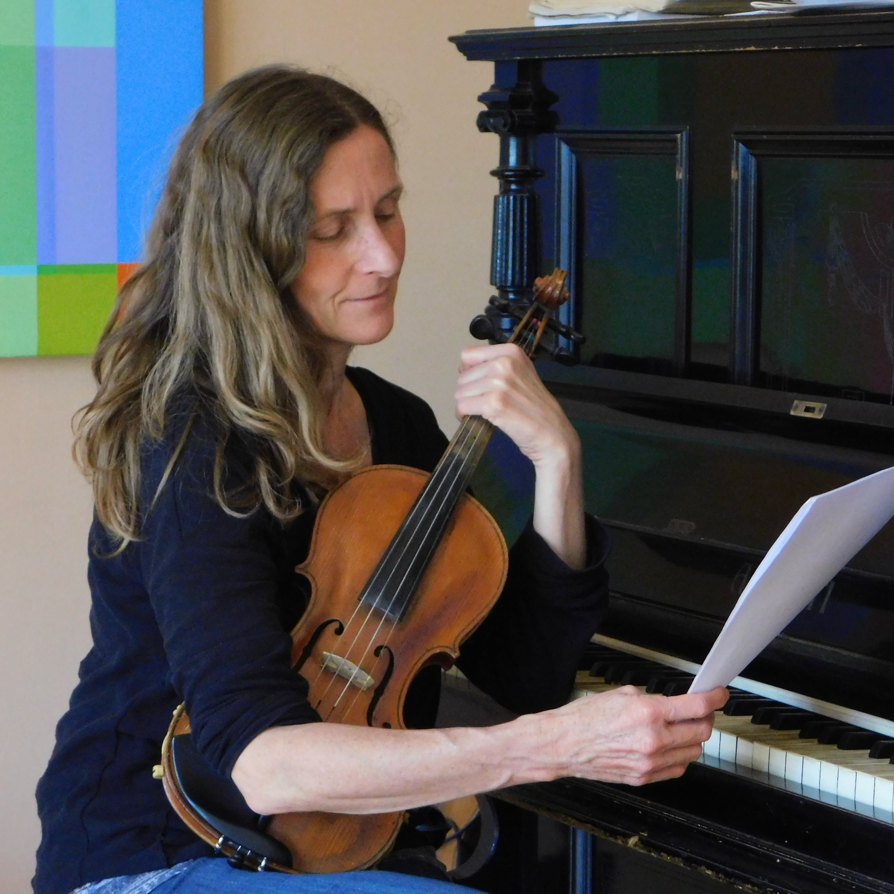 profesora con violín examinando una partitura en Taller Artístico Los Pinos