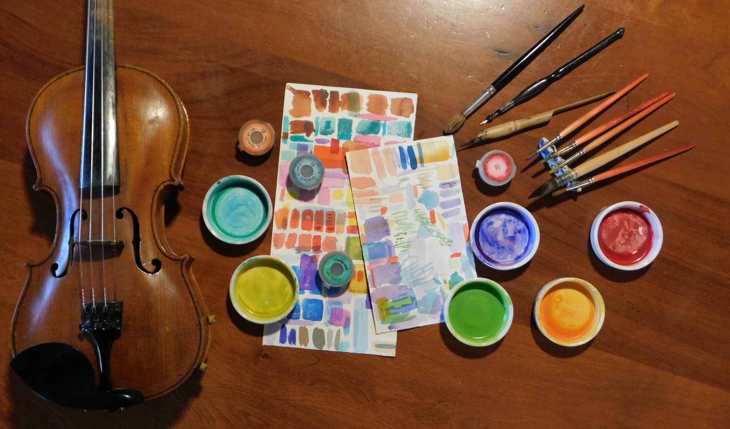 violín, pinceles, pocillos de pintura y tiras de colores